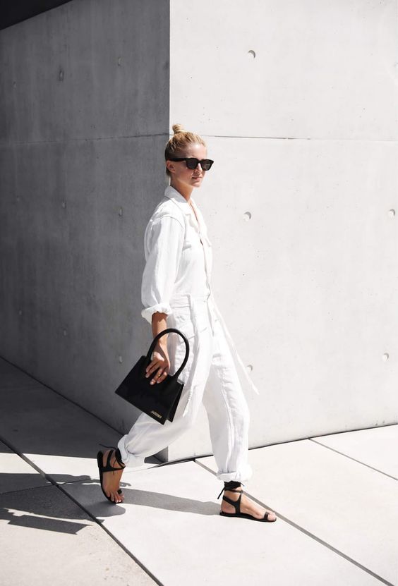 model wearing white jumpsuit and black bag