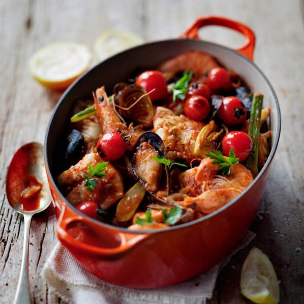 Le Creuset orange volcanic casserole dish with seafood stew recipe