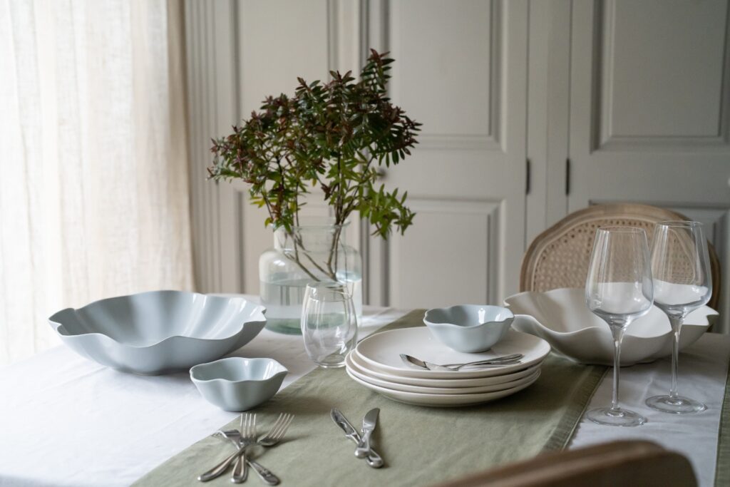 Dining table set with white Sophie Conran plates, grey tablecloth and green table runner and a plant